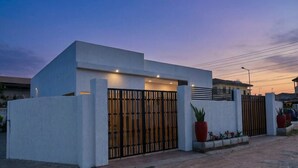 A modern house with a gated entrance, a concrete exterior, and a driveway leading to the front door.