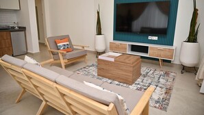 A modern living room with a sofa, a wooden coffee table, a TV, and potted plants.
