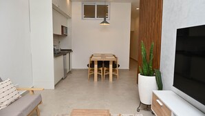 A modern living space with a dining area, kitchen, and a large flat-screen TV. - The Chelsea TownHouse B (Accra)
