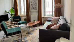 Ein modernes Wohnzimmer mit einer Couch, einem Couchtisch, einem Fernseher und einer Pflanze.