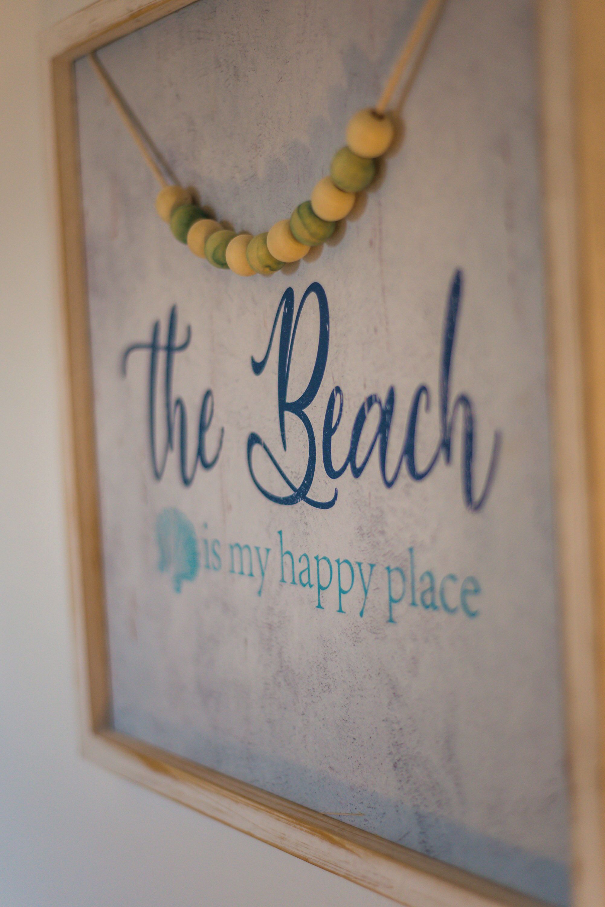 Een lijst met de tekst 'het strand is mijn geluksmoment' en een decoratieve kralenketting.