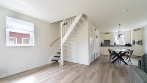 A spacious living area with a staircase, a dining table with chairs, and a kitchen area with a microwave.