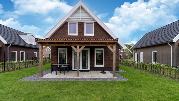 A modern house with a covered patio, a lawn, and a neighboring house.
