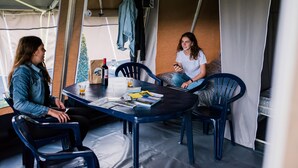 A tented dining area with a table, chairs, and a bottle of wine.