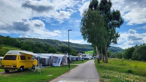A campsite with a yellow van, tents, and a paved path.