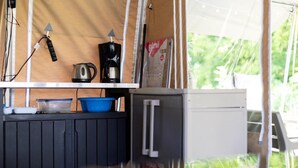 A compact kitchen area with a kettle, coffee maker, and a small refrigerator.