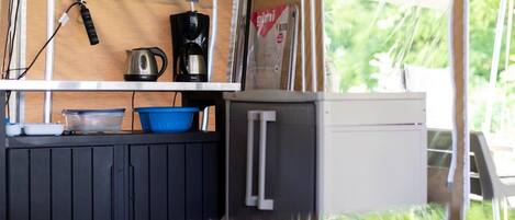 Eine kompakte Küchenzeile mit Wasserkocher, Kaffeemaschine und kleinem Kühlschrank.