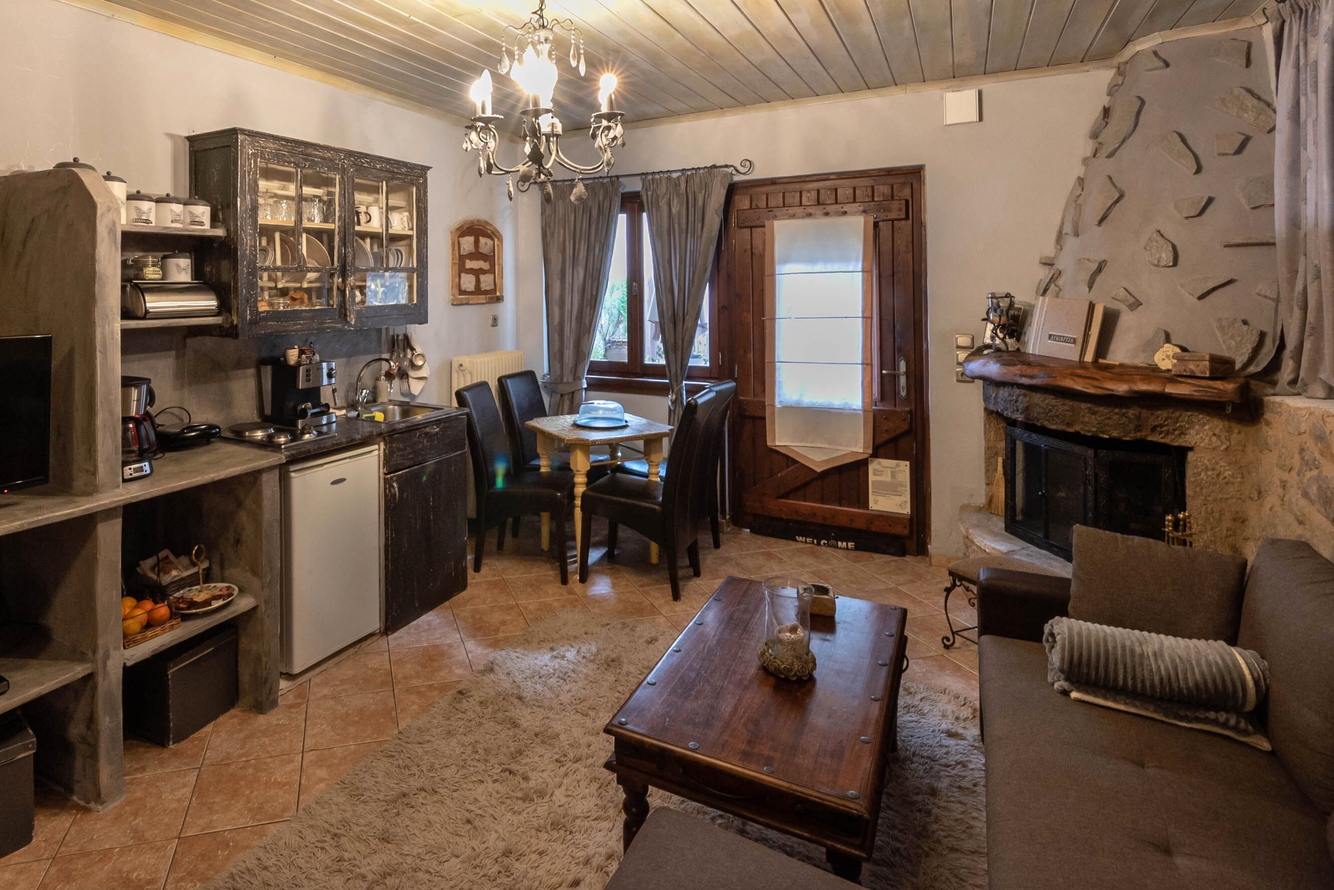 A cozy living room with a fireplace, a dining area with a table and chairs, and a kitchen with cabinets and a refrigerator.