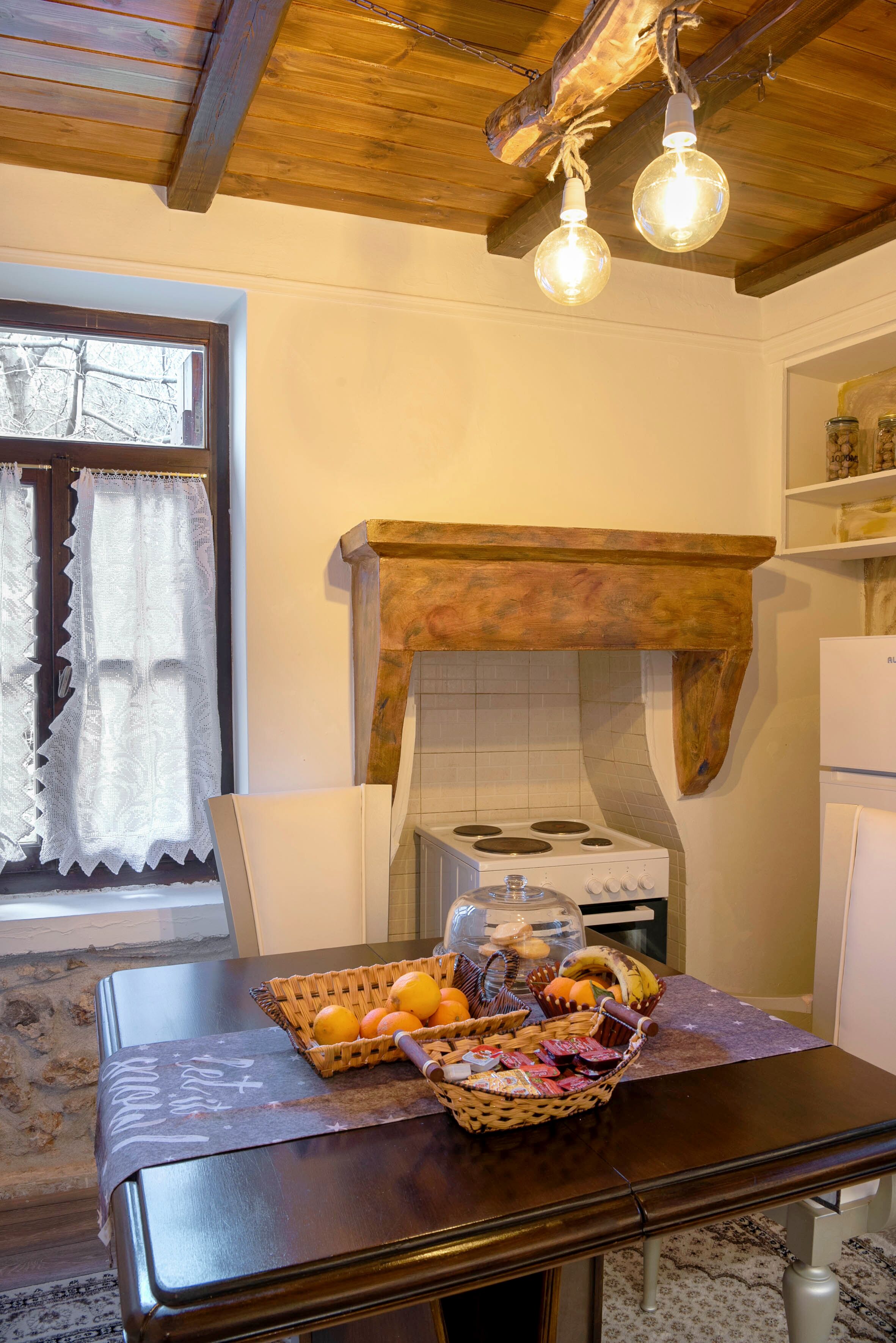A kitchen with a wooden ceiling, a stove, and a basket of fruits on a table.