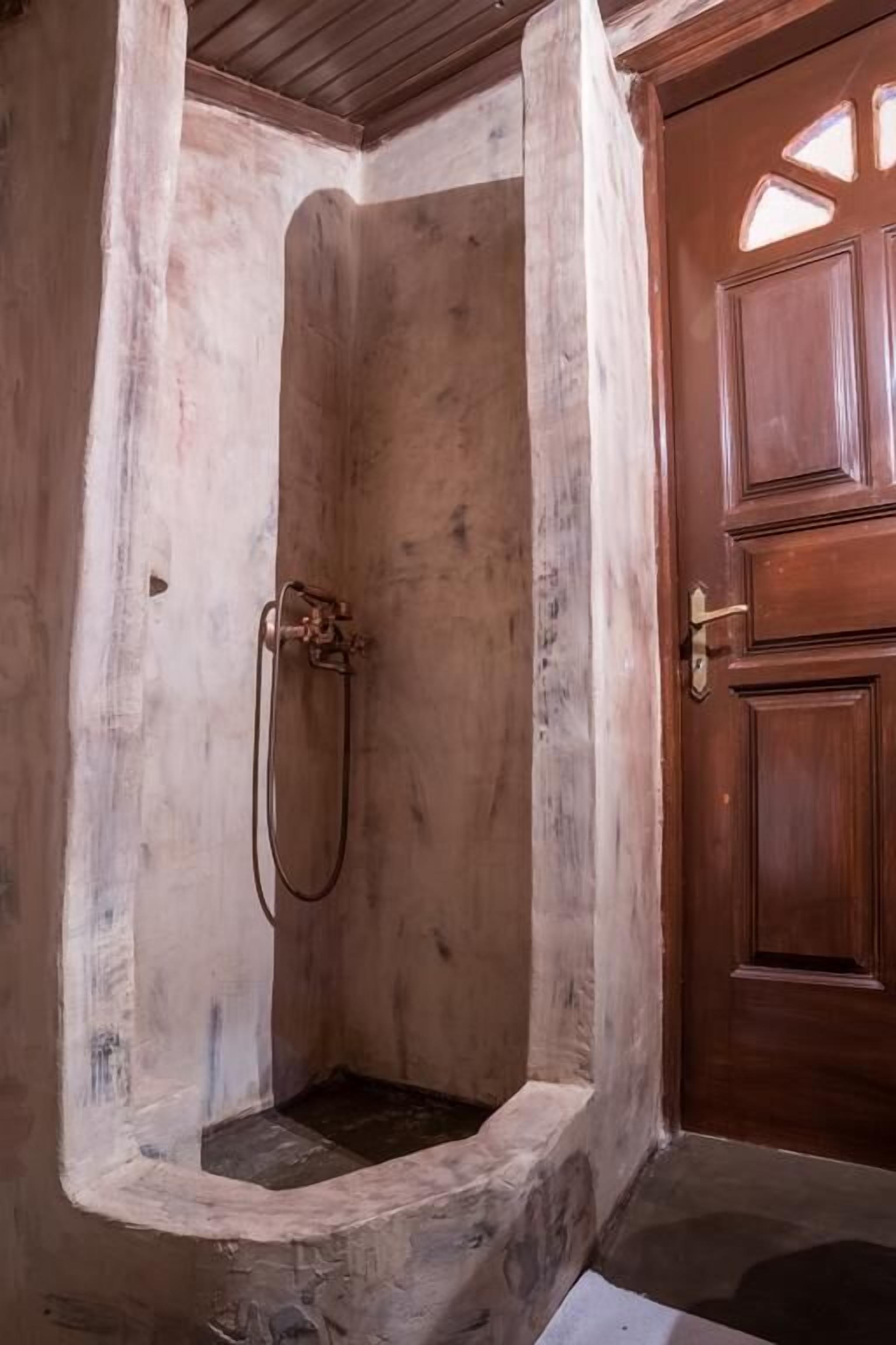 Un espace douche doté d’une porte en bois et d’un pommeau de douche.