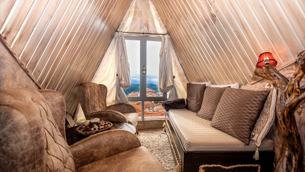 Ein gemütlicher, zeltartiger Raum mit einem Bett, zwei Sofas und einem kleinen Tisch.