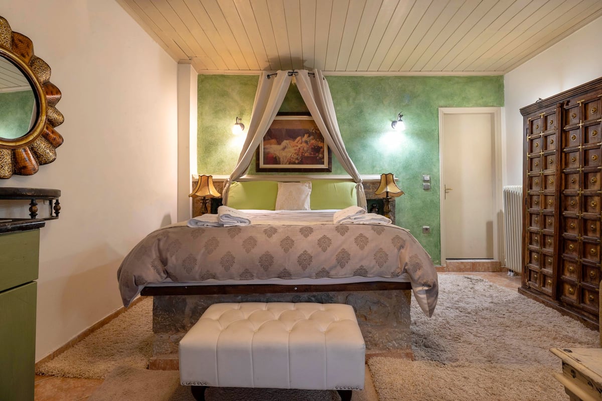 Une chambre à coucher avec un lit, un banc, un miroir et une armoire.