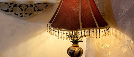 A lamp with a red shade and decorative trim on a wooden table.