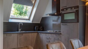 A modern kitchen with a skylight, built-in oven, and a dining area with leather chairs. - Holiday Home near Biesbosch & Breda (Oosterhout)