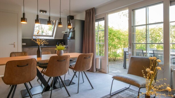 A modern dining area with a long table, chairs, and pendant lights. - Holiday Home near Biesbosch & Breda (Oosterhout)