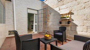 A patio area with wicker furniture, a basket of fruit, and a stone wall. - 3729 Pio Apartment by Barbarhouse (Lecce)
