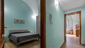 A bedroom with a bed, a wooden wardrobe, a telephone, and a floral artwork on the wall. - 3729 Pio Apartment by Barbarhouse (Lecce)