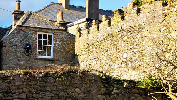 A stone building with a chimney, a window, and a barbecue grill.