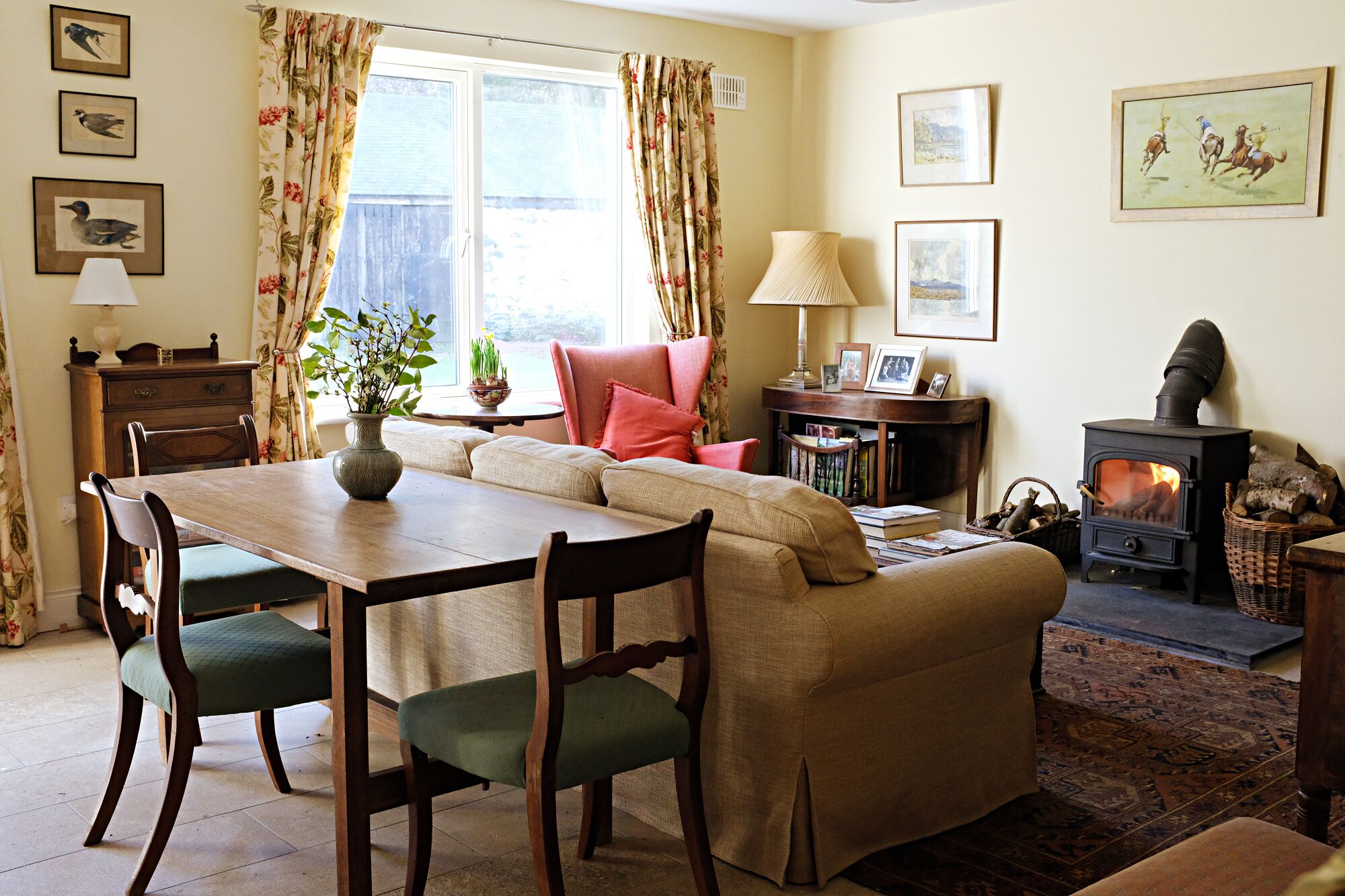 A cozy living room with a sofa, a dining table, chairs, a fireplace, and a window with curtains.