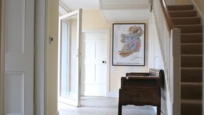 A hallway with a wooden bench, a staircase, and a map on the wall.
