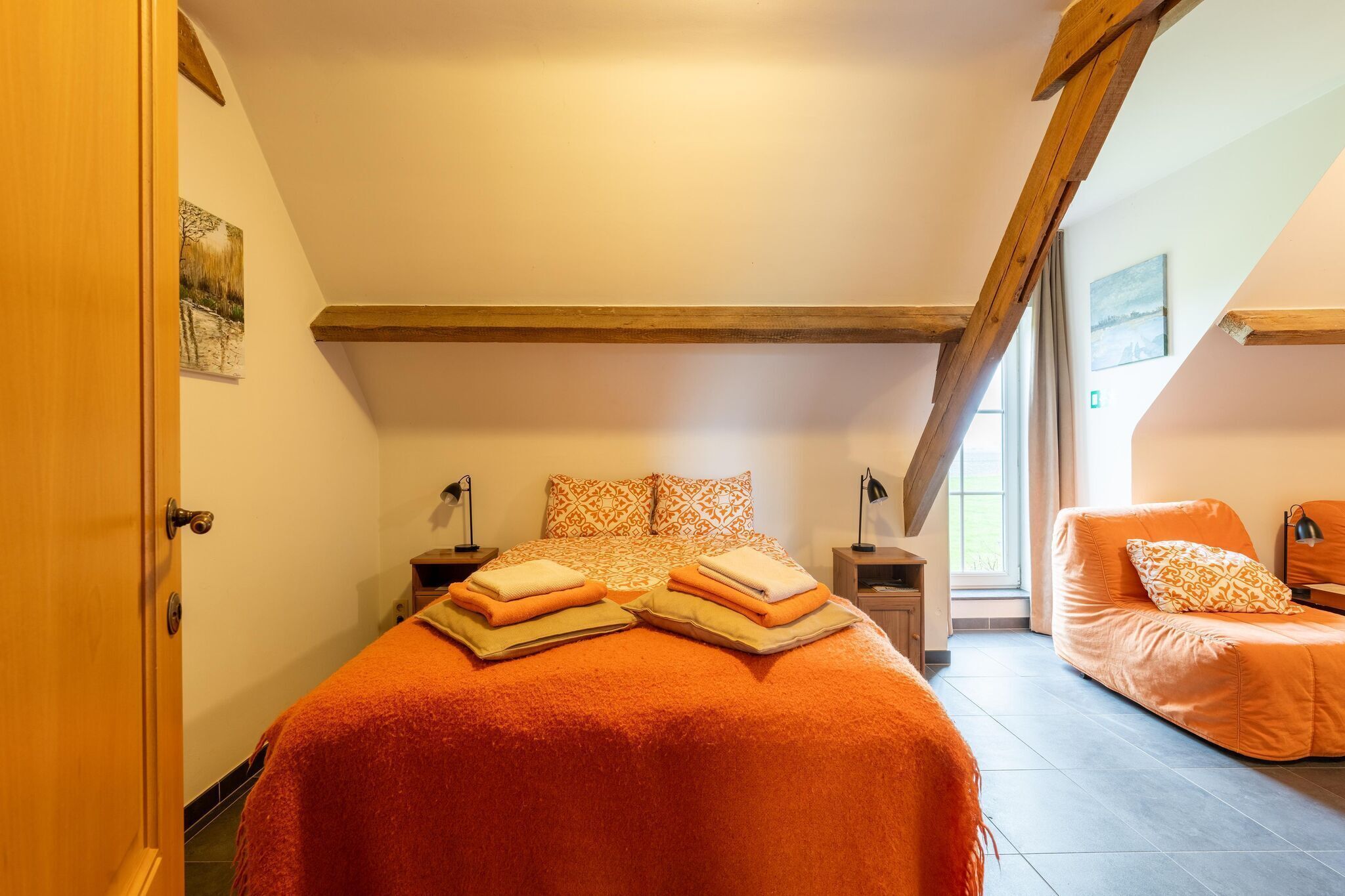 A bedroom with a bed, a sofa, a window, and a door.