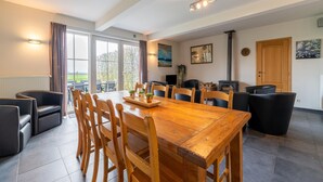 Un vaste espace dédié à la salle à manger, avec une table et des chaises en bois, une cheminée et une grande fenêtre donnant sur l’extérieur.