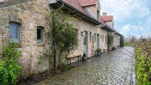 A stone building with a cobblestone courtyard, a bench, and potted plants. - Apartment on Belgium's Stunning Coastline (Diksmuide)