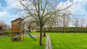 A playground with a slide and a climbing structure, surrounded by a well-maintained lawn and a stone pathway. - Apartment on Belgium's Stunning Coastline (Diksmuide)