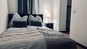 Un lit bien fait, avec une literie à motifs, une lampe de chevet et une table de nuit.