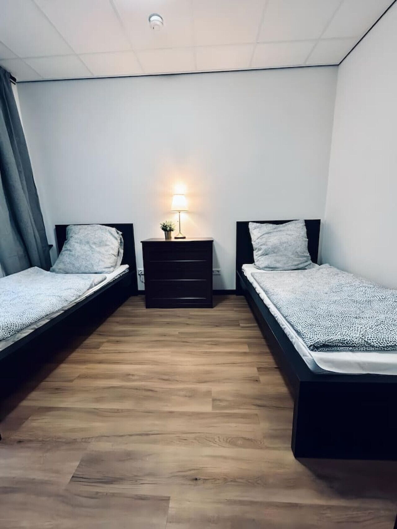 Ein Schlafzimmer mit zwei Einzelbetten, einem Nachttisch mit Lampe und Holzboden.