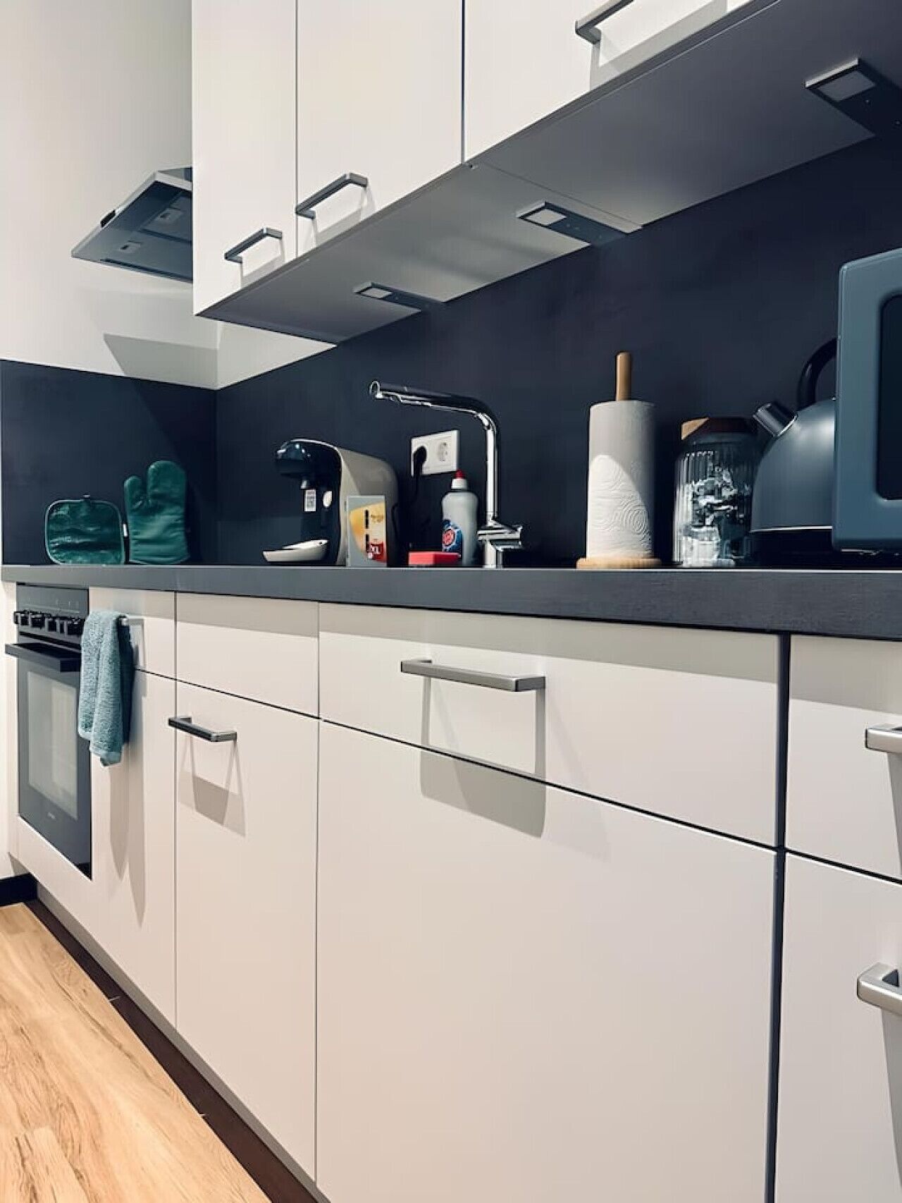 A modern kitchen with white cabinets, stainless steel appliances, and a black countertop.