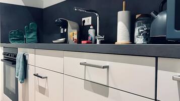 A modern kitchen with white cabinets, stainless steel appliances, and a black countertop.