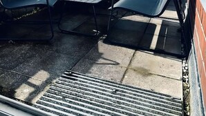 Terrassa al terrat amb mobiliari exterior, vista d'un edifici modern i una agulla d'església al fons.