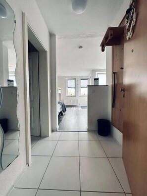 Un pasillo con piso de baldosas que lleva a un dormitorio con cama y radiador.