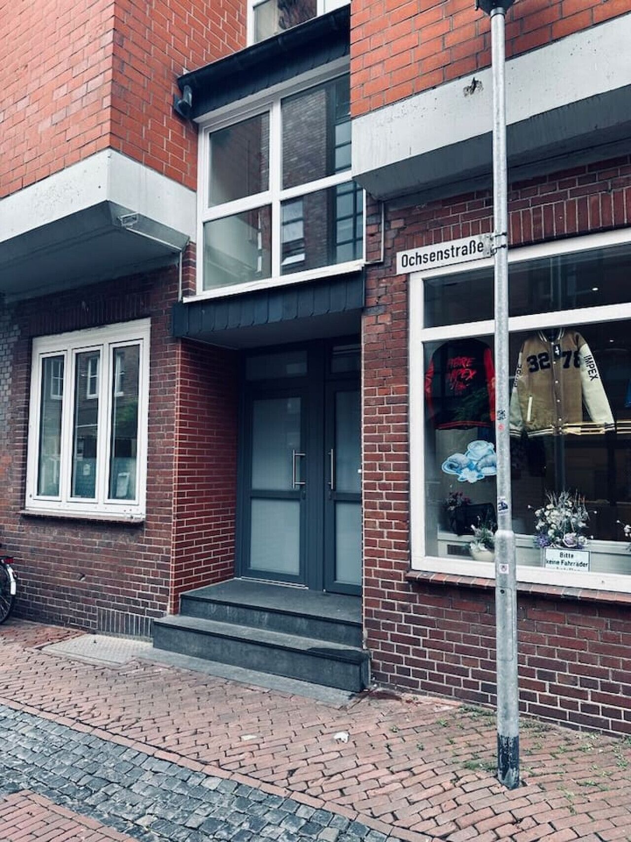 A two-story building with a brick facade, a black awning over the entrance, and a sign reading "Ochsenstraße".