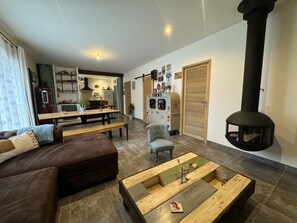 A living room with a sofa, a coffee table, a fireplace, and a kitchen in the background.