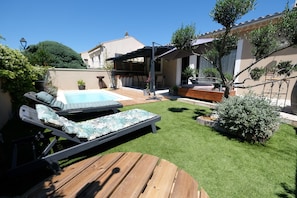 A backyard with a pool, lounge chairs, a wooden table, and a pergola.