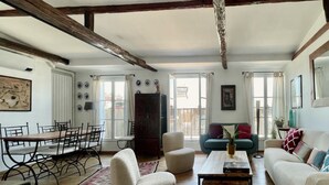 A spacious living room with a wooden dining table, white sofas, and a coffee table.