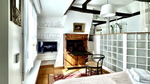 A bedroom with a bed, a desk, a chair, a television, and a bookshelf.