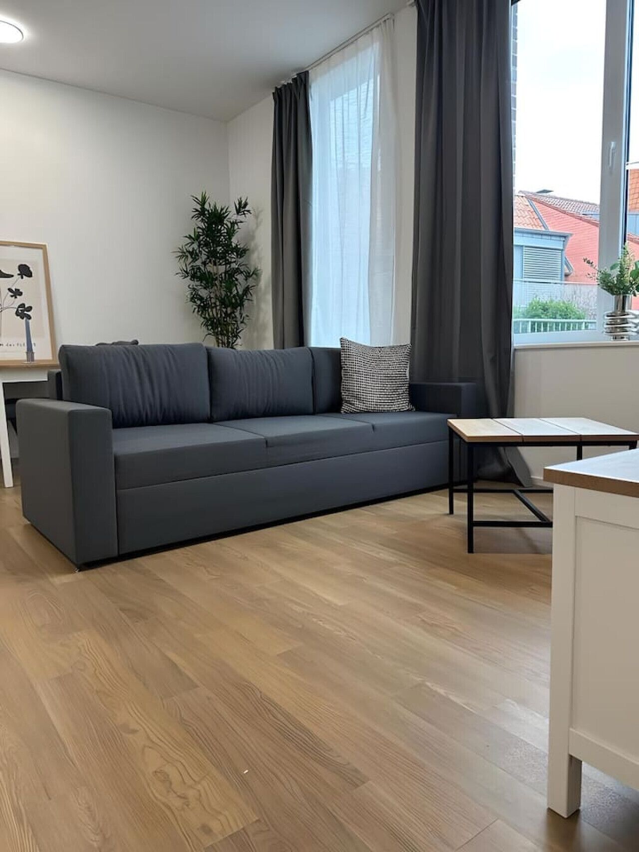 Un salon moderne avec un canapé gris, une petite table et une plante en pot.