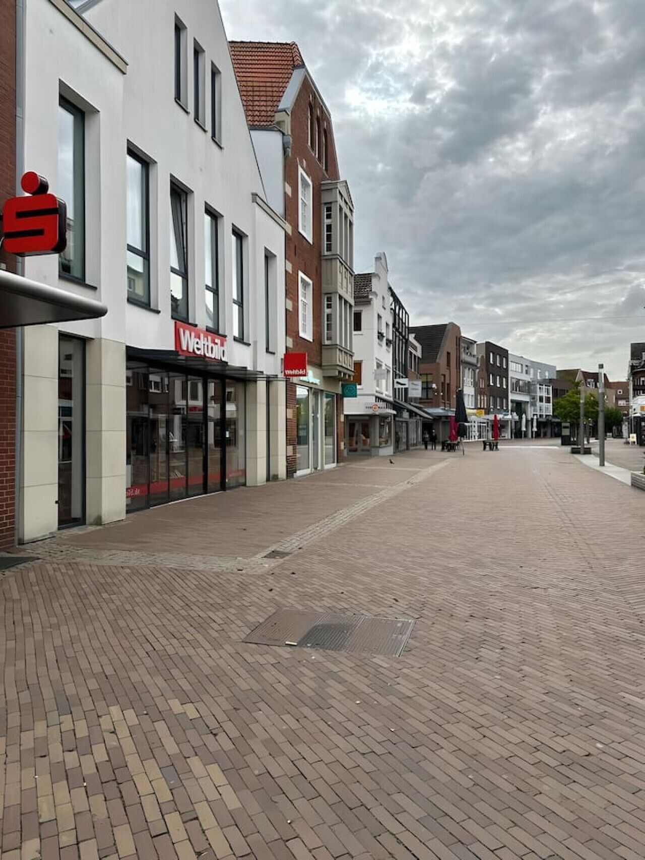 Une rue piétonne bordée de boutiques, avec un ciel dégagé.