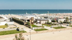 Un hotel frente a la playa con una piscina grande, sombrillas y vistas al mar.