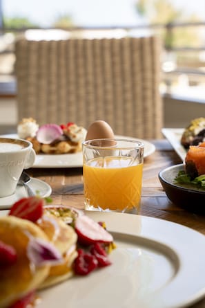 A breakfast setting with a plate of pancakes, a glass of orange juice, and a cup of coffee on a wooden table.