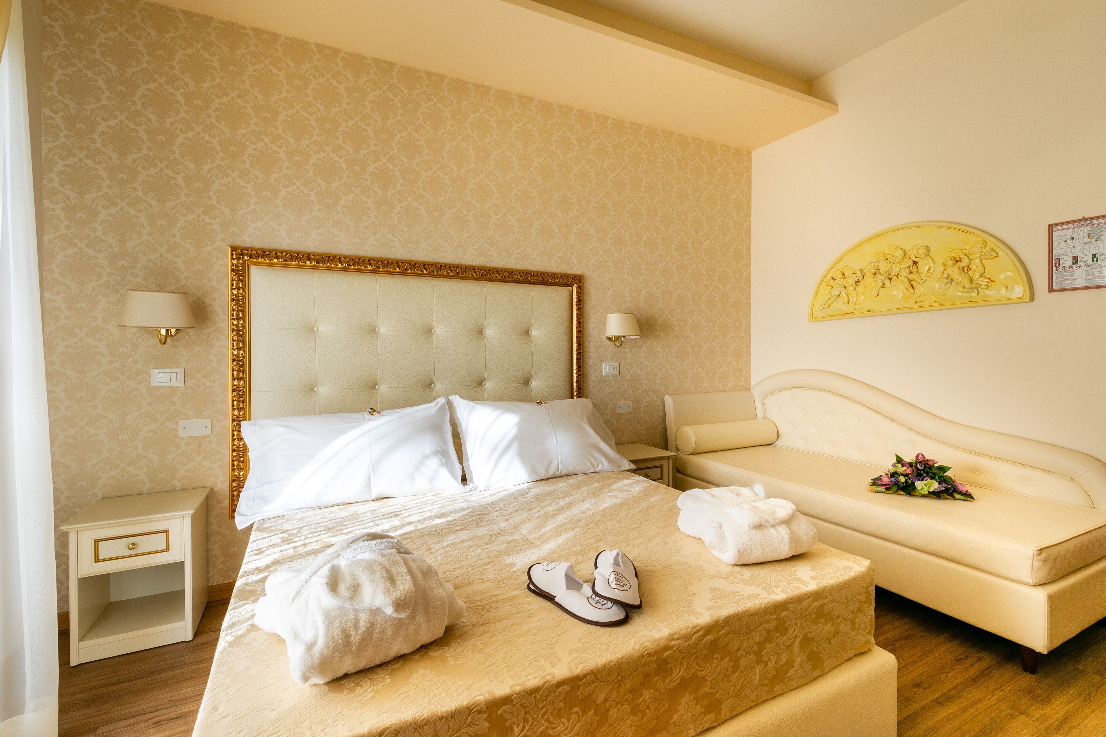 Ein Hotelzimmer mit einem großen Bett, einer Couch, einem Nachttisch und einem an der Wand befestigten Kunstwerk.