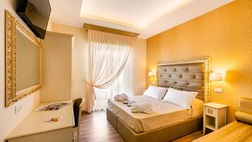 Habitación de hotel con una cama grande, mesitas de noche, un escritorio y televisión.