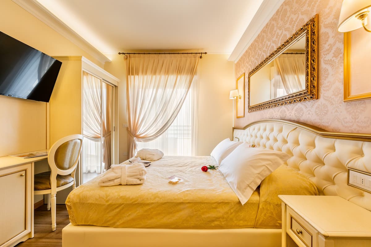 A hotel room with a large bed, a desk, a chair, and a TV.