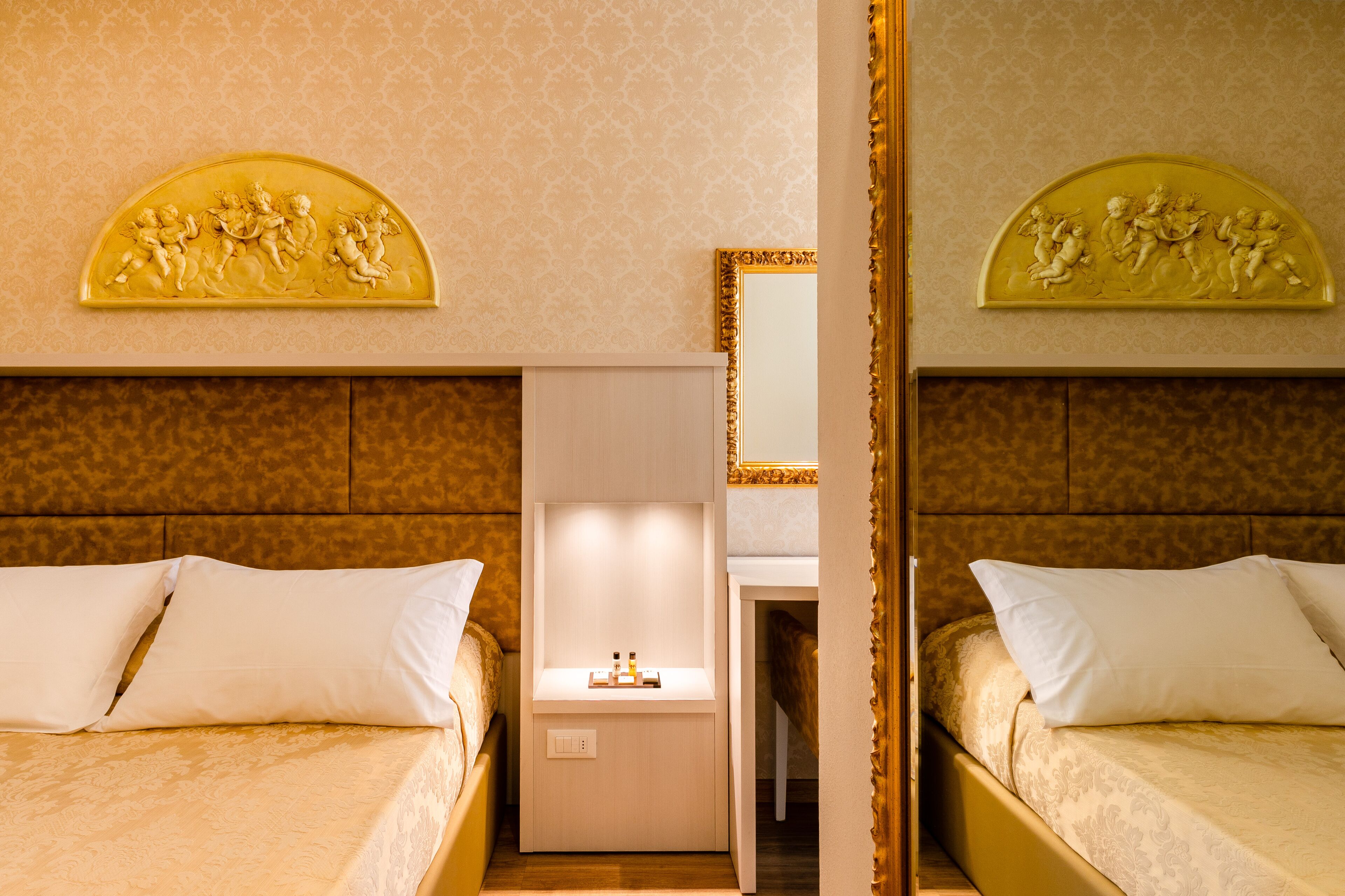 Ein Hotelzimmer mit zwei Betten, einem Nachttisch, einem Spiegel und einer dekorativen Wandverkleidung.