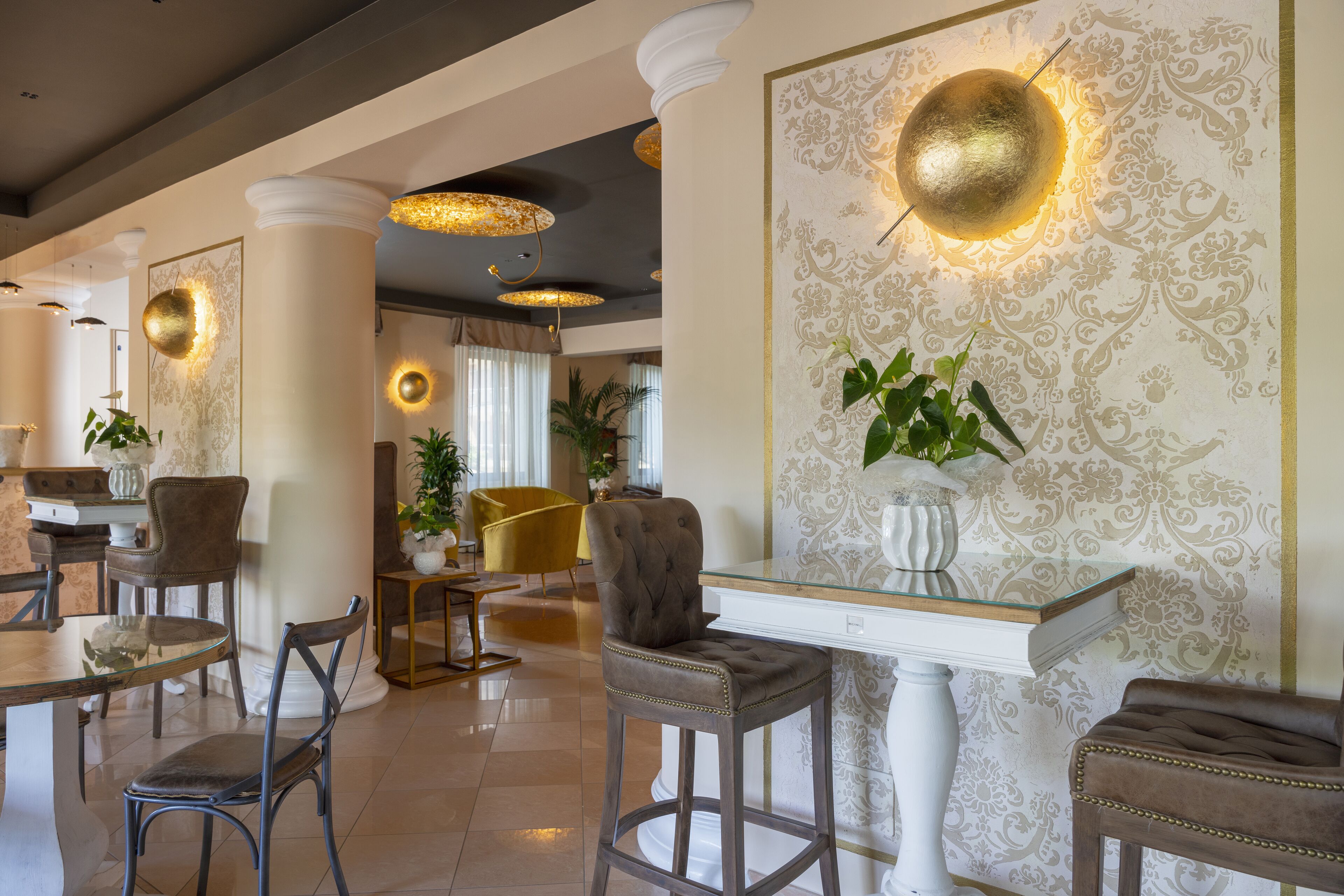Un'ampia hall con soffitti alti, decorazioni elaborate alle pareti e lampade dal design moderno.