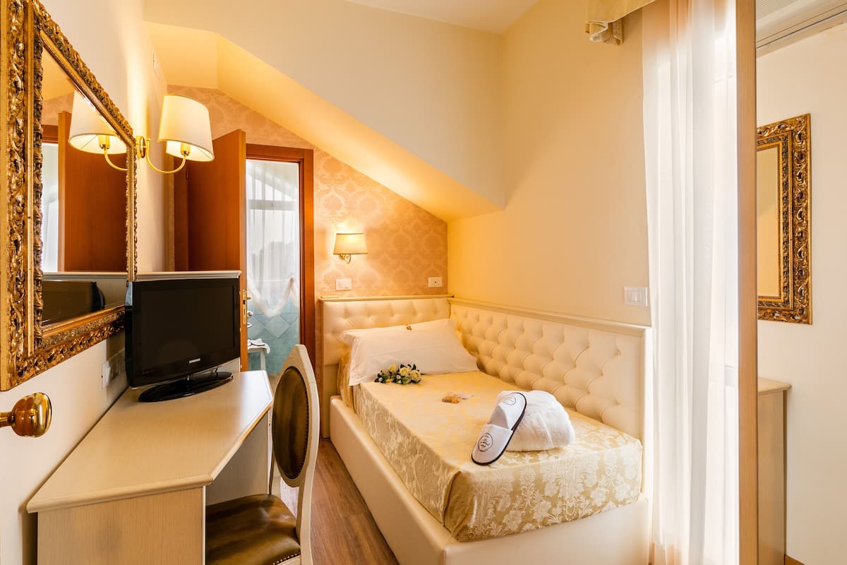 A hotel room with a bed, a television, a desk, and a mirror.