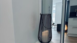 A modern interior with a white fluffy stool, a black metal chair, and a wooden floor. - Absolute Bestlage Wohnung Artic I (Nordhorn)